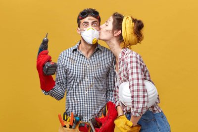 pretty-female-kissing-her-husband-cheek-being-thankful-him-repairing-her-wardrobe-surprised-male-worker-mask-holding-drilling-machine-being-glad-receive-kiss-from-his-girlfriend